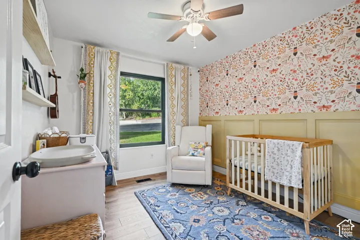 Wood-finish flooring, ceiling fan, board and batten wall detailing, and a prominent window
