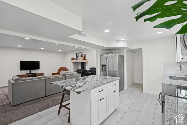 Kitchen island with a light-toned countertop, white cabinetry with dark hardware, and recessed lighting