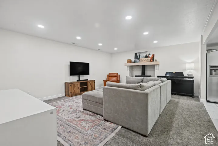 Recessed lighting, white walls, carpeted flooring, built-in shelving, and a white mantel