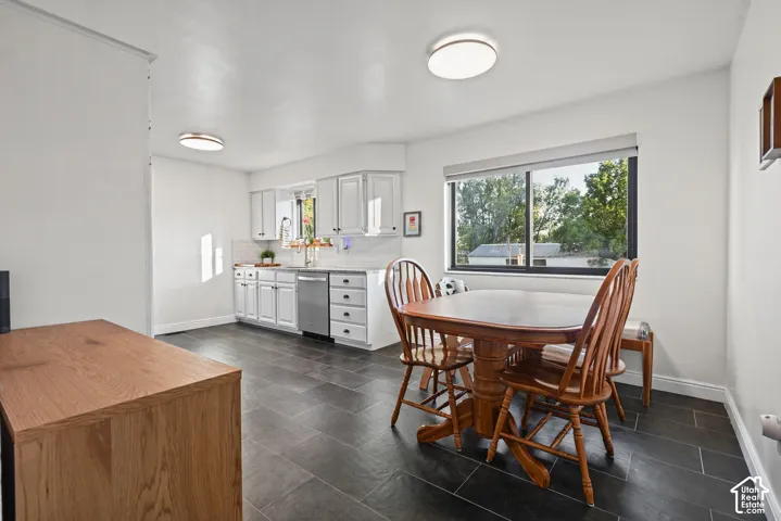 Kitchen featuring white cabinetry, stainless steel appliances, a white tile backsplash, and dark tile flooring
