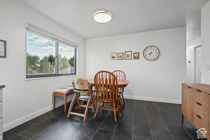 Large window, dark tile flooring, white walls, and flush-mount ceiling light