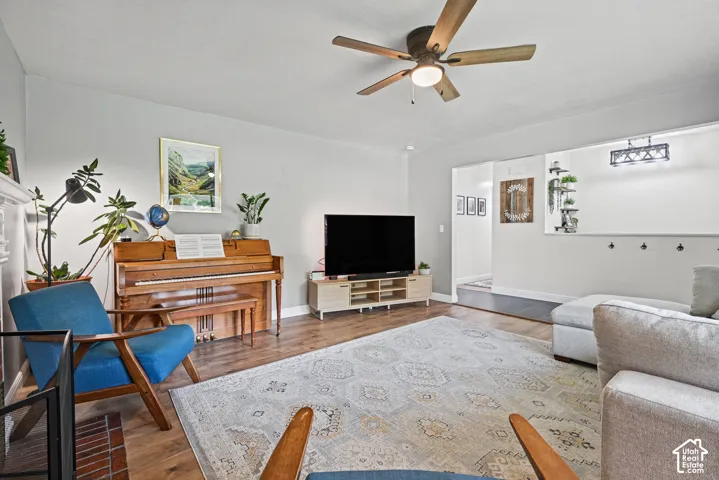 Wood-finish flooring, ceiling fan with integrated lighting, recessed lighting, and a decorative wall fixture