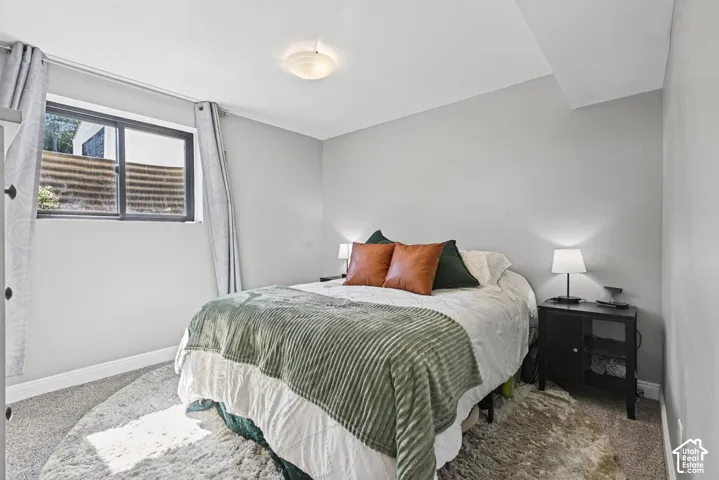 Neutral wall paint, carpet flooring, a window with horizontal blinds, and a flush mount ceiling light fixture