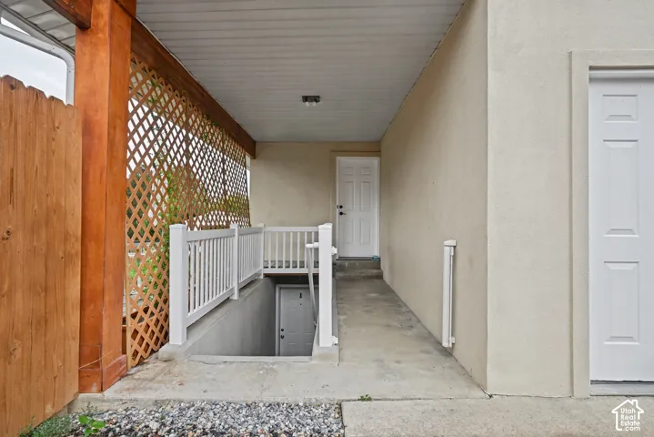 Covered outdoor walkway featuring a lattice privacy screen, wood-finish privacy fence, and white railing