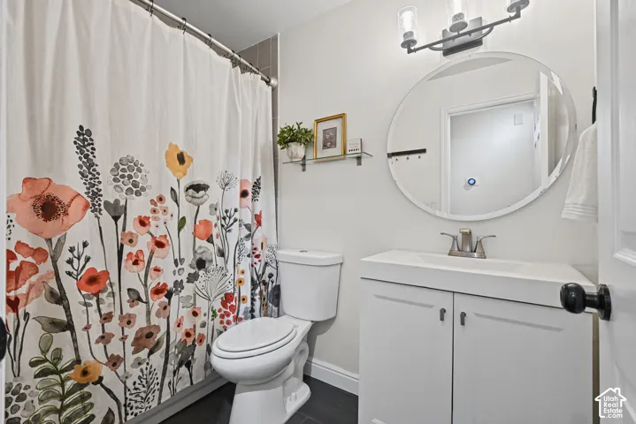 White vanity with integrated sink, circular mirror, and dark-finish three-light fixture