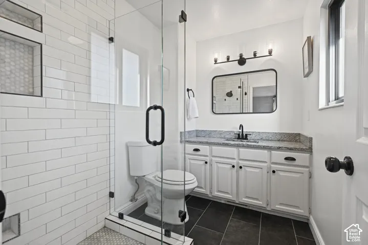Glass-enclosed shower with white subway tile and hexagonal floor tile
