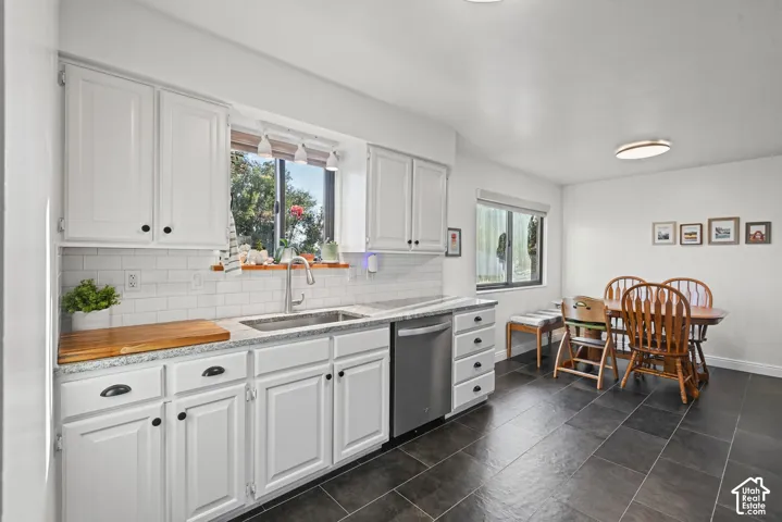 White cabinetry with black hardware, subway tile backsplash, stainless steel sink, and granite-look countertops