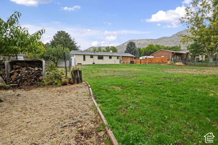 Expansive yard space featuring a mix of gravel and green areas, mature trees, and a mountain backdrop