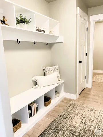Built-in white storage bench with open shelving, integrated coat hooks, and coordinating overhead cubbies