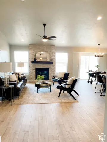 Wood-finish flooring, stone-clad fireplace with mantel, recessed lighting, ceiling fan, and sliding glass door