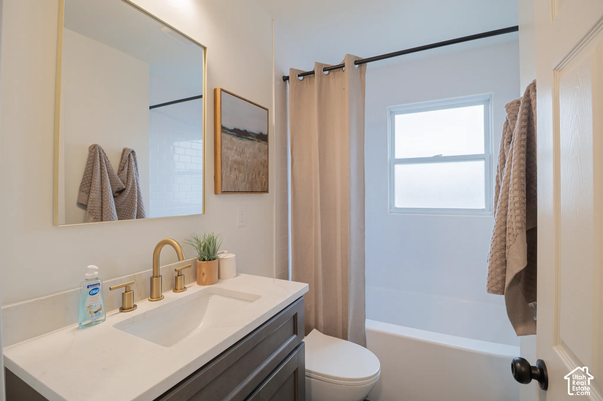 Vanity with a light-colored countertop and gold-toned faucet