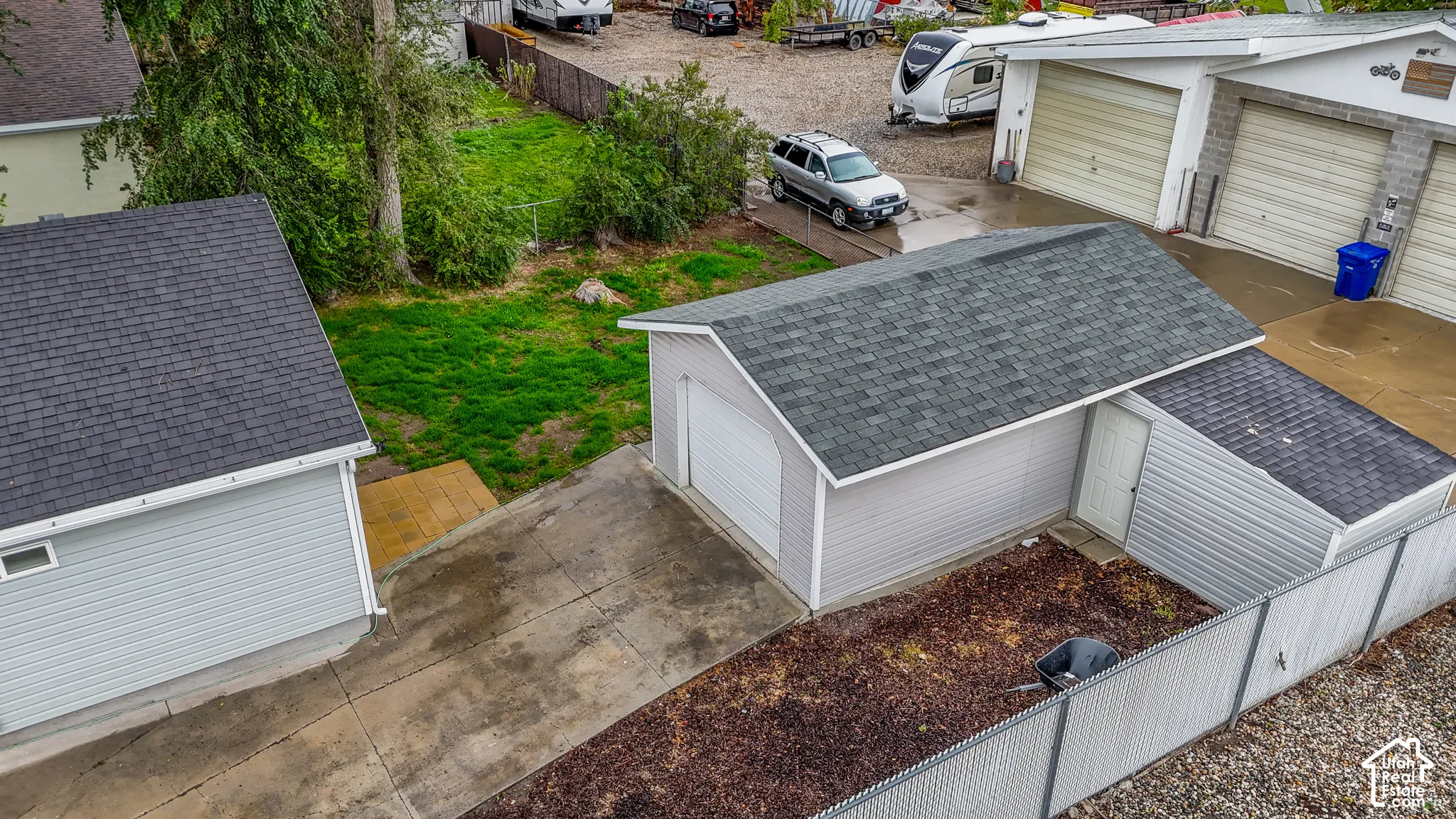 Detached garage with a shingled roof, accompanied by an additional utility structure