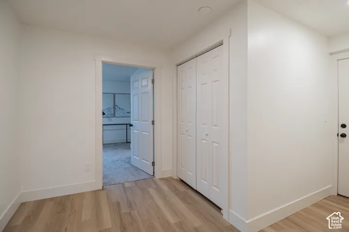 Light wood-finish flooring, white walls, white trim, and a white bi-fold closet door