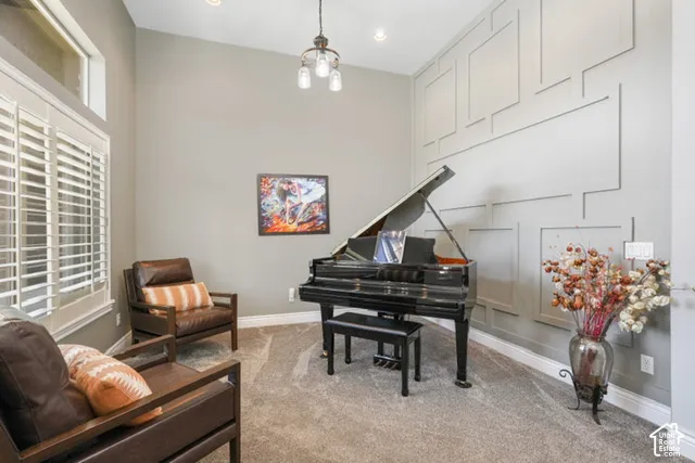 Vaulted ceiling with an industrial-style chandelier, decorative wall paneling, plantation shutters, and recessed lighting