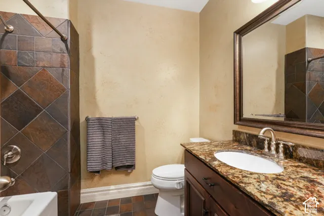 Bathroom featuring a dark wood vanity with a granite-style countertop, an undermount sink with a brushed nickel faucet, a framed mirror, and a tiled shower surround with a bronze-toned shower rod