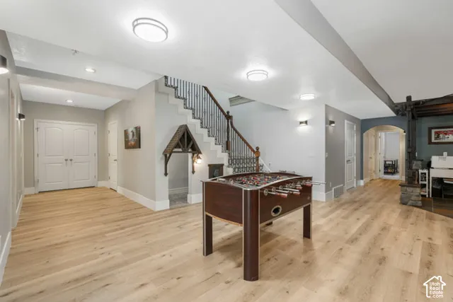 Hardwood-style flooring throughout, staircase with wrought iron railing, arched entryways, recessed lighting, and wall sconces
