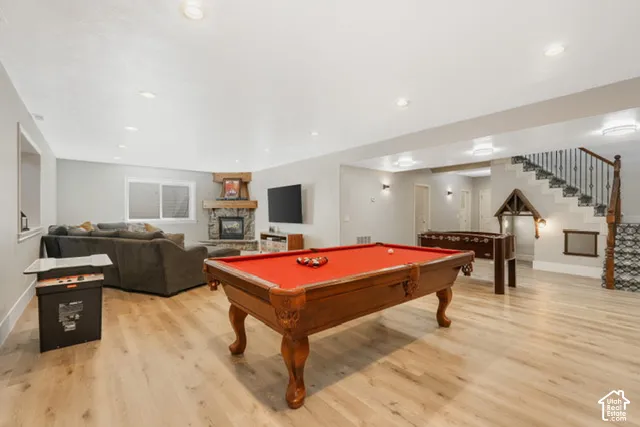 Spacious recreation area featuring wood-finish flooring, recessed lighting, and a stone-clad fireplace