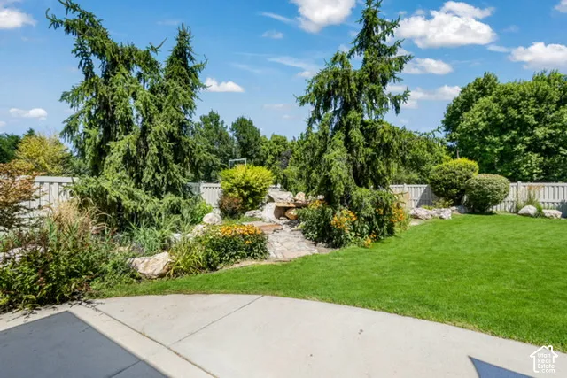 Expansive lawn area with a stone-lined garden, established trees, and a concrete patio
