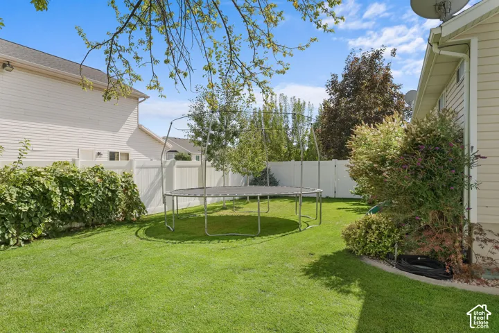 Expansive yard featuring a manicured lawn, established landscaping, and a privacy fence