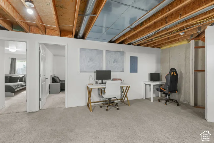Carpeted room with exposed ceiling joists and unfinished concrete wall