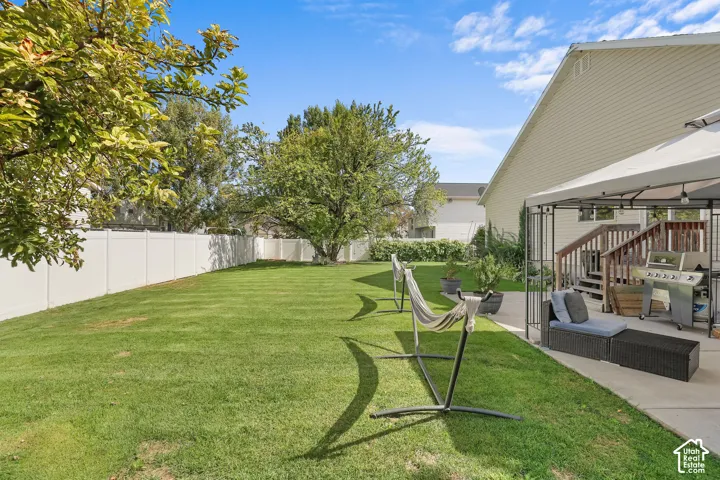 Spacious backyard with a manicured lawn, white privacy fencing, and mature trees