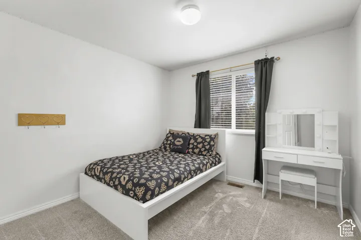 Bright room featuring a window with blinds, light-colored walls, and carpet flooring