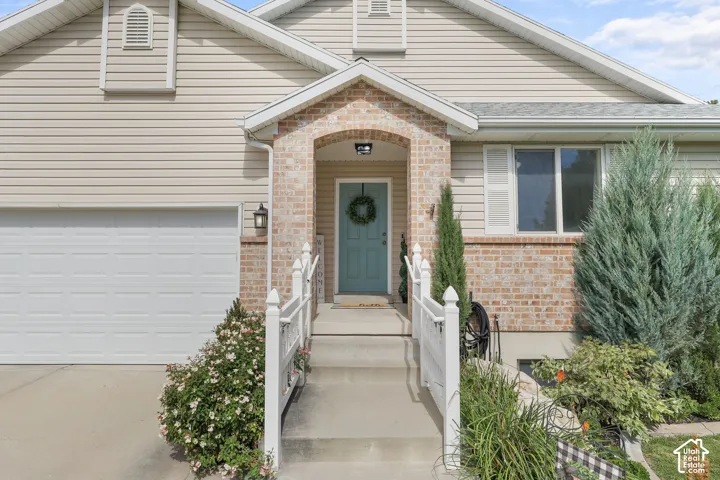 Brick and siding exterior with an attached garage, covered entryway, and front landscaping