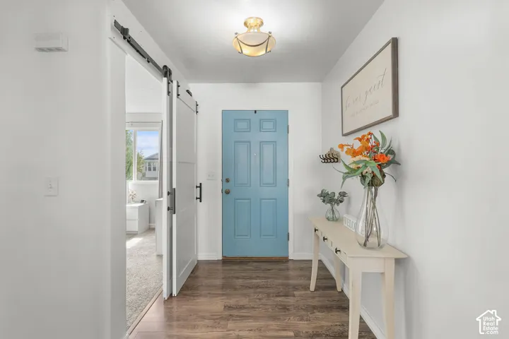 Entryway with wood-finish flooring, a light blue paneled door, and a sliding barn door with black hardware