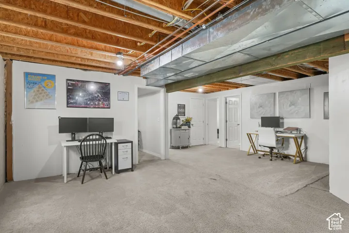 Open-concept room with light gray carpeting and exposed ceiling joists