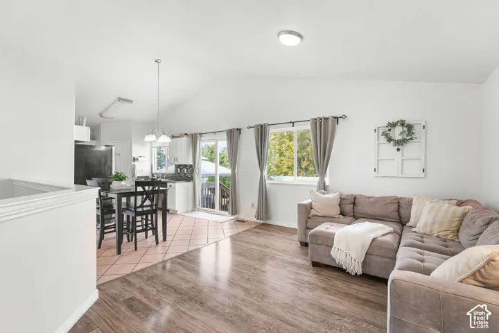 Vaulted ceiling, wood-finish flooring, kitchen with tile flooring, built-in cabinetry, and sliding glass door