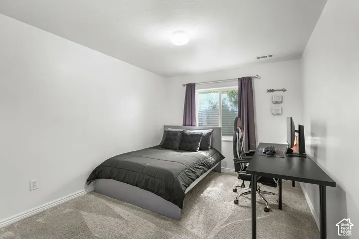 Light-toned wall finishes, carpet flooring, a window with horizontal blinds, and a ceiling-mounted light fixture