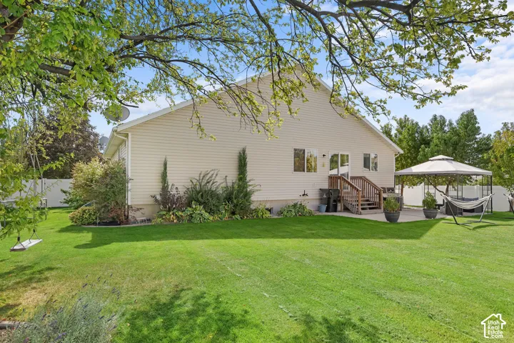 Expansive grassy yard with mature trees, a private patio, and a wood deck