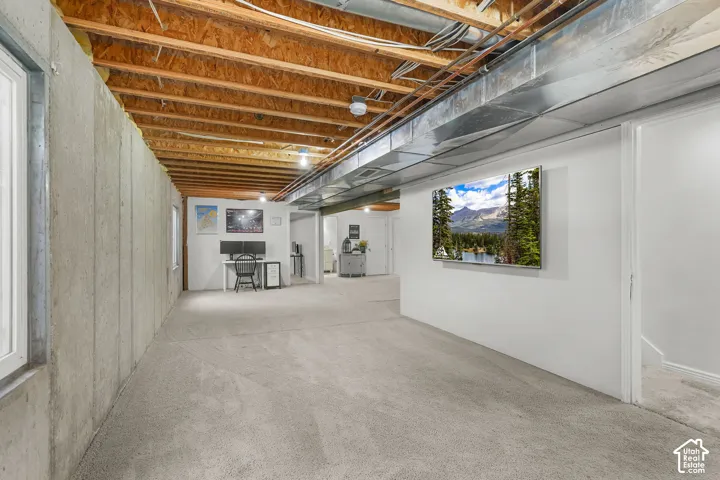 Exposed ceiling joists and ductwork, concrete foundation walls, light-colored carpeting, and recessed lighting fixtures