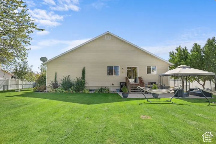 Expansive green lawn with a privacy fence, wood deck, and concrete patio