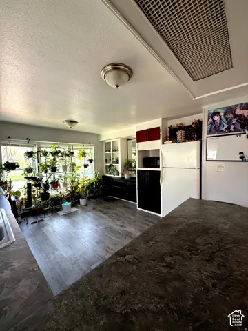 Kitchen featuring expansive countertops, built-in cabinetry, wood-finish flooring, recessed lighting, and a white refrigerator