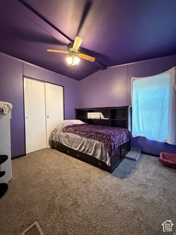 Carpeted flooring, vaulted ceiling, and built-in closet with sliding doors