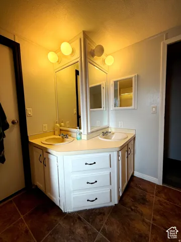 Dual vanity with white cabinetry, built-in sinks, and individual mirrors