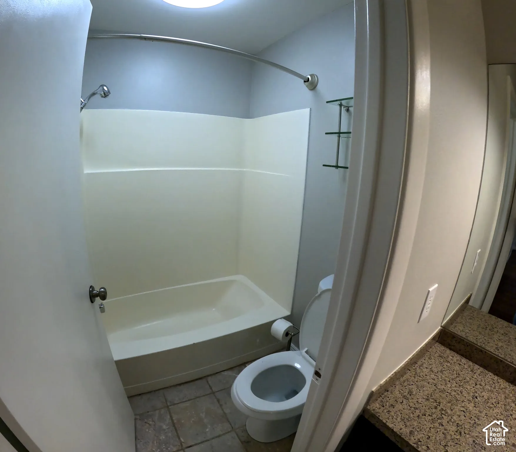 Full bathtub with shower fixture and tiled flooring.