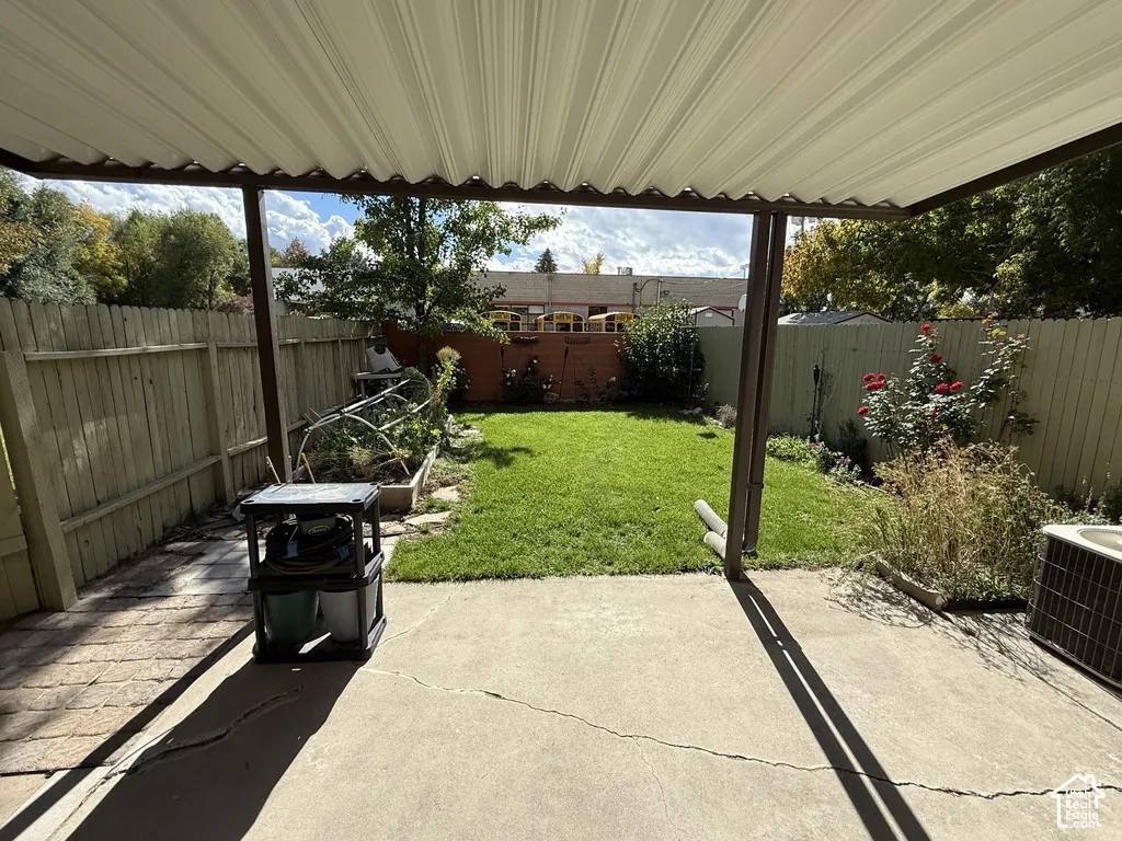 Covered patio with concrete flooring, wood privacy fencing, and a grassy yard