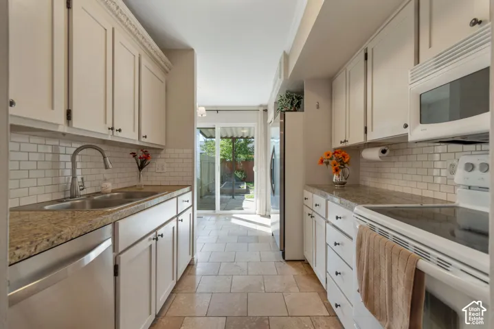 Kitchen featuring light-toned cabinetry, light-toned countertops, subway tile backsplash, and tile flooring