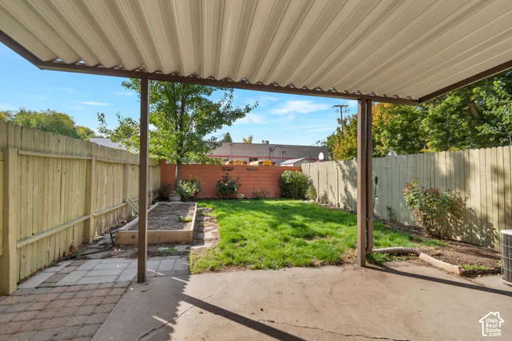 Backyard featuring a covered patio, wood privacy fencing and a raised garden bed.