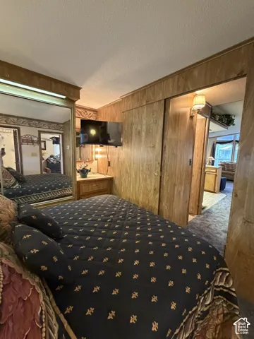 Bedroom featuring wood-panel walls, carpeted flooring, and mirrored closet doors