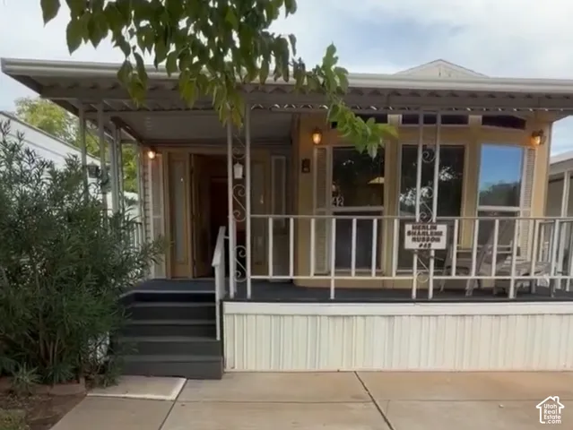 Covered front porch with decorative railing, multiple windows, steps to entrance, and concrete pathway