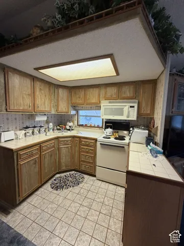 Kitchen featuring wood-finish cabinetry, tile countertops, and tile flooring
