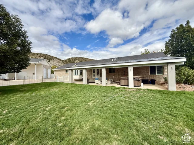 Expansive lawn area with a covered patio, brick exterior, and a detached garage structure