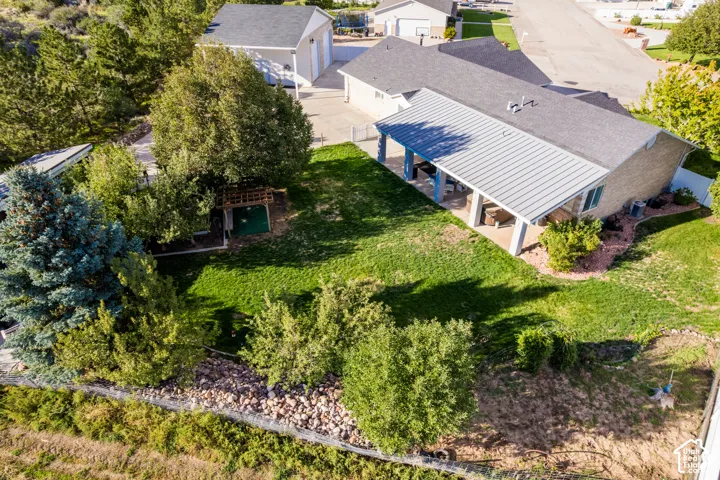 Expansive backyard featuring a covered patio, manicured lawn, and mature trees