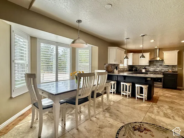 Kitchen featuring white upper cabinetry, dark lower cabinetry, a mosaic tile backsplash, and a central island with pendant lighting