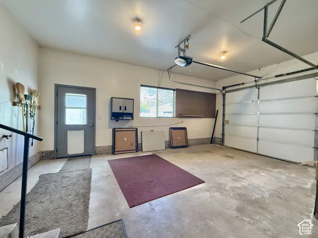 Single-car garage with a paneled overhead door, concrete flooring, and an interior access door featuring a transom window