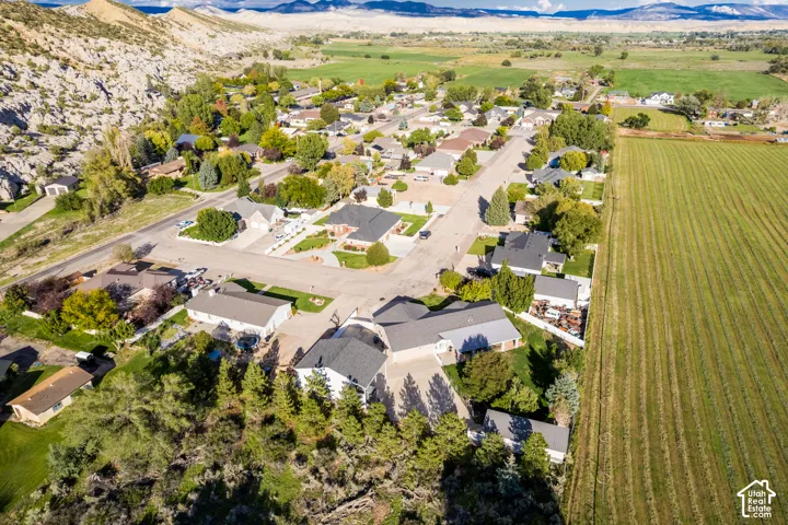 Residential neighborhood featuring established homes, paved streets, bordering agricultural fields, and natural rock formations
