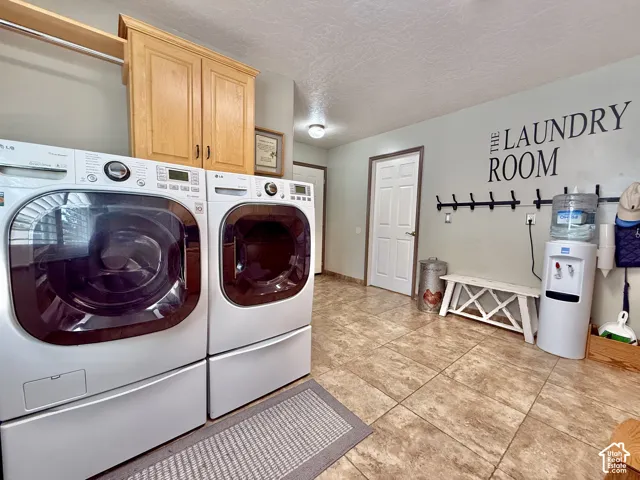Laundry room featuring built-in cabinetry, upper shelving with hanging rod, and tiled flooring